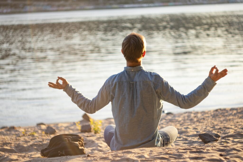 A man meditating at the beach.